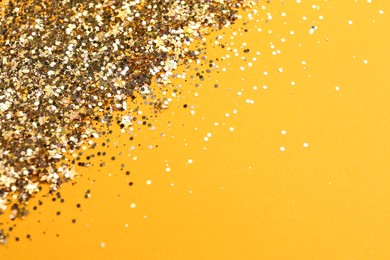 Shiny bright golden glitter on pale orange background. Space for text