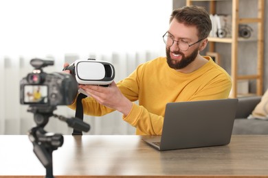 Photo of Smiling technology blogger recording video review about virtual reality headset at home