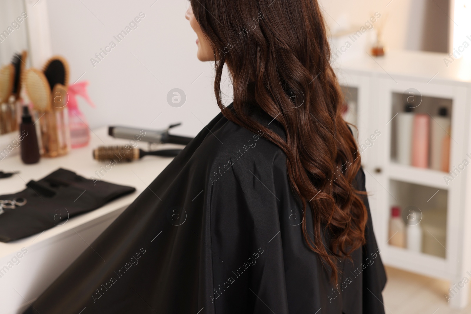 Photo of Woman with curly hair sitting in salon, closeup