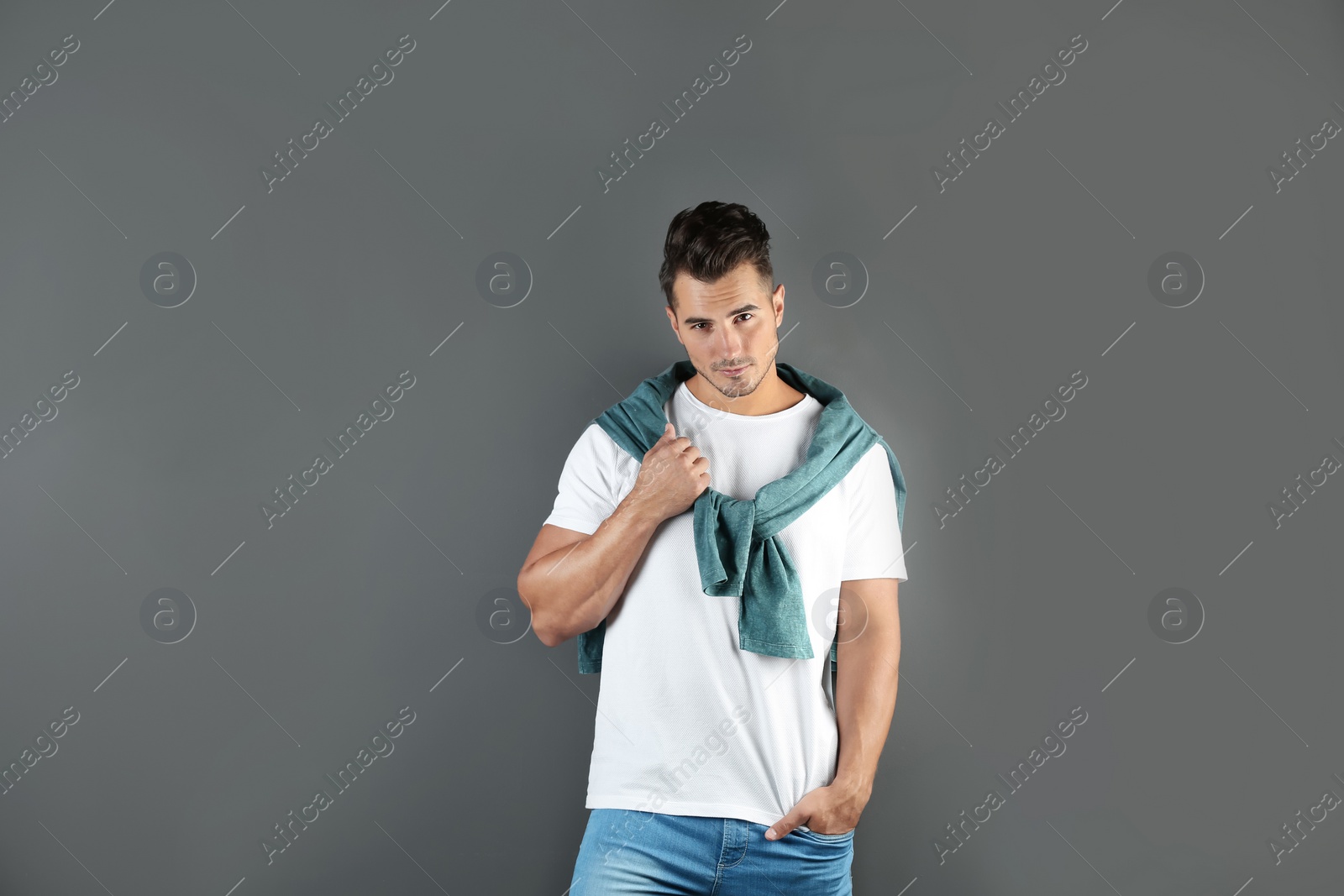 Photo of Young man in stylish jeans on grey background