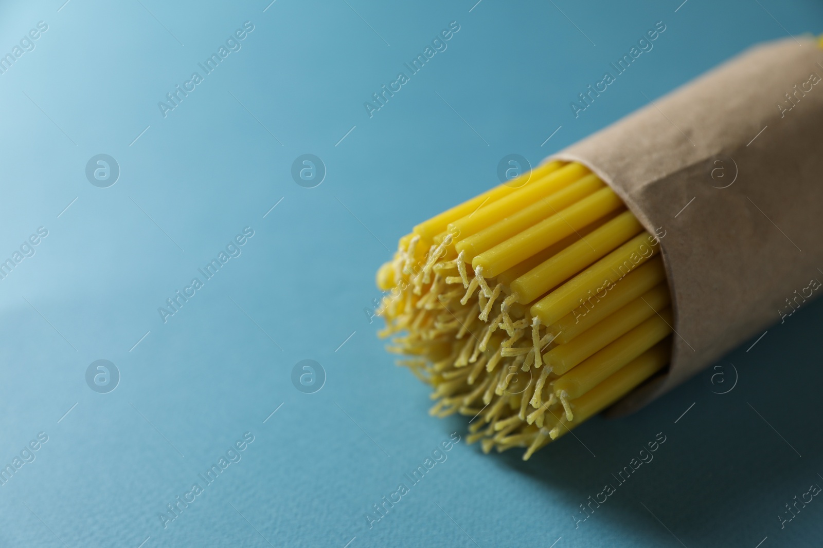 Photo of Many church wax candles on light blue background, closeup. Space for text