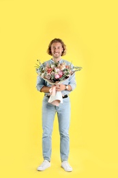 Photo of Young handsome man with beautiful flower bouquet on yellow background