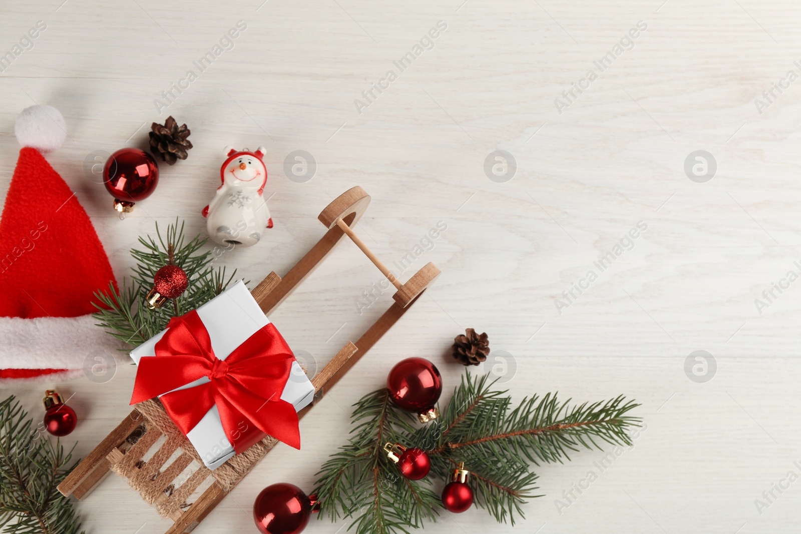 Photo of Beautiful Christmas composition with miniature sleigh on white wooden table, flat lay. Space for text