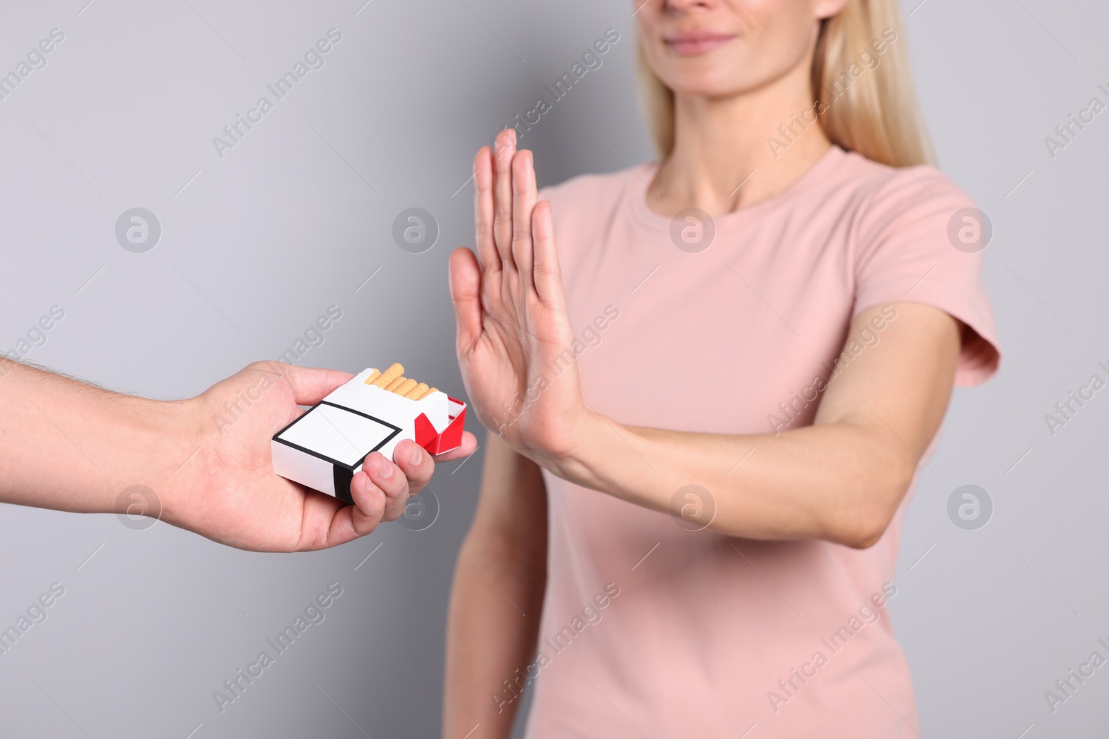 Photo of Woman refusing cigarettes on light grey background, selective focus. Quitting smoking concept