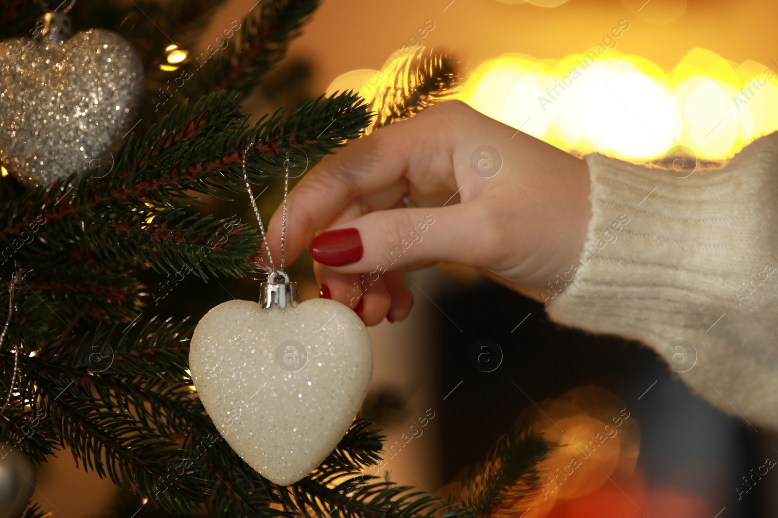 Photo of Woman decorating Christmas tree at home, closeup