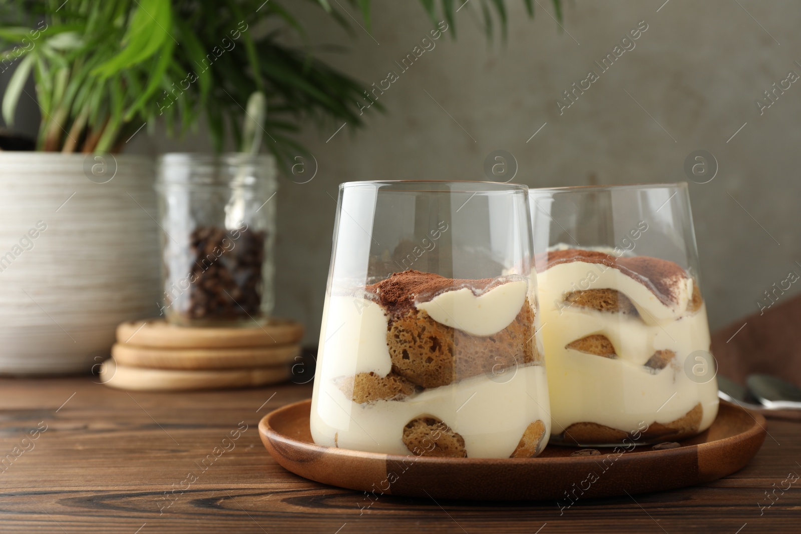 Photo of Delicious tiramisu in glasses on wooden table, space for text