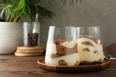 Delicious tiramisu in glasses on wooden table, space for text