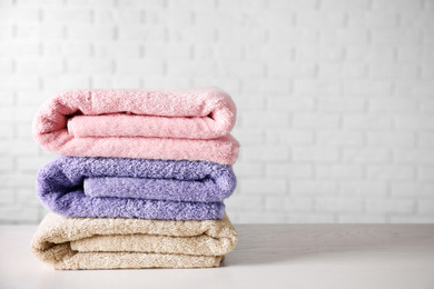 Photo of Stack of clean bath towels on white wooden table. Space for text