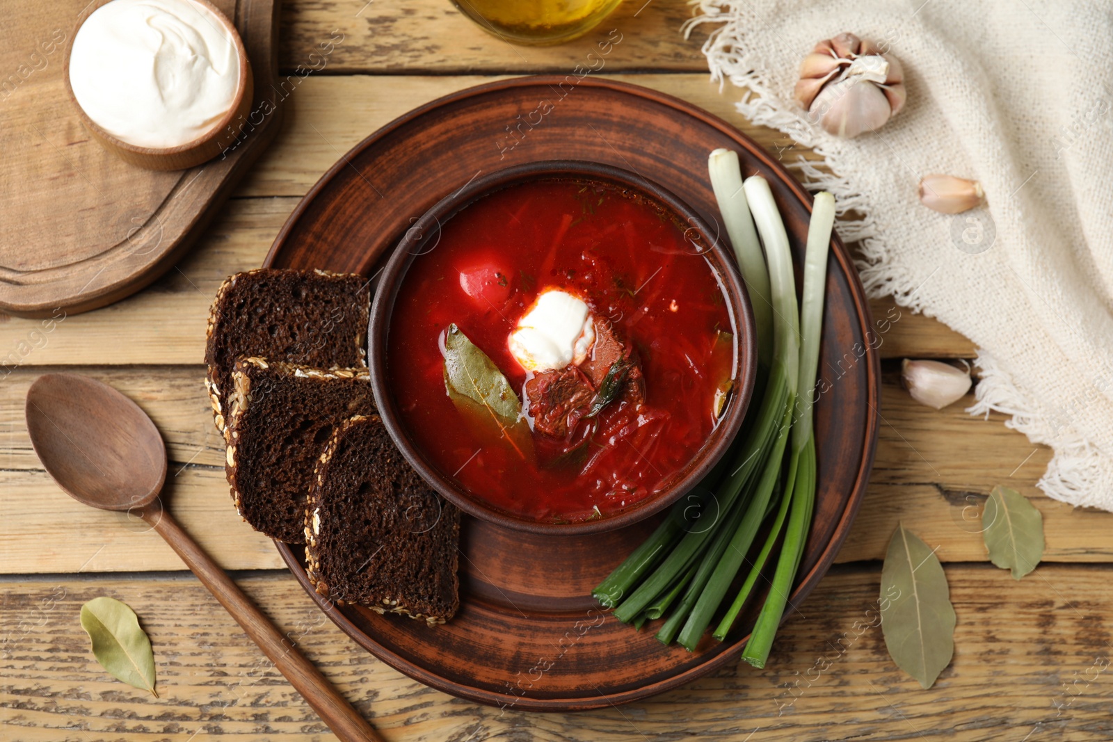 Photo of Clay bowl with Ukrainian borsch served on wooden table, flat lay