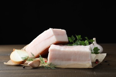 Photo of Tasty salt pork with herbs, onion and garlic on wooden table