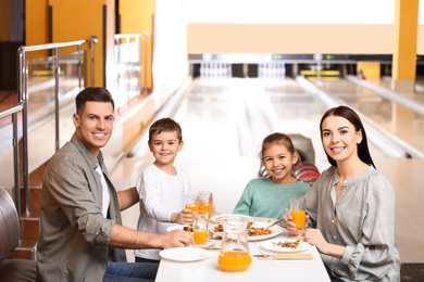 Photo of Happy family with pizza and drinks in bowling club