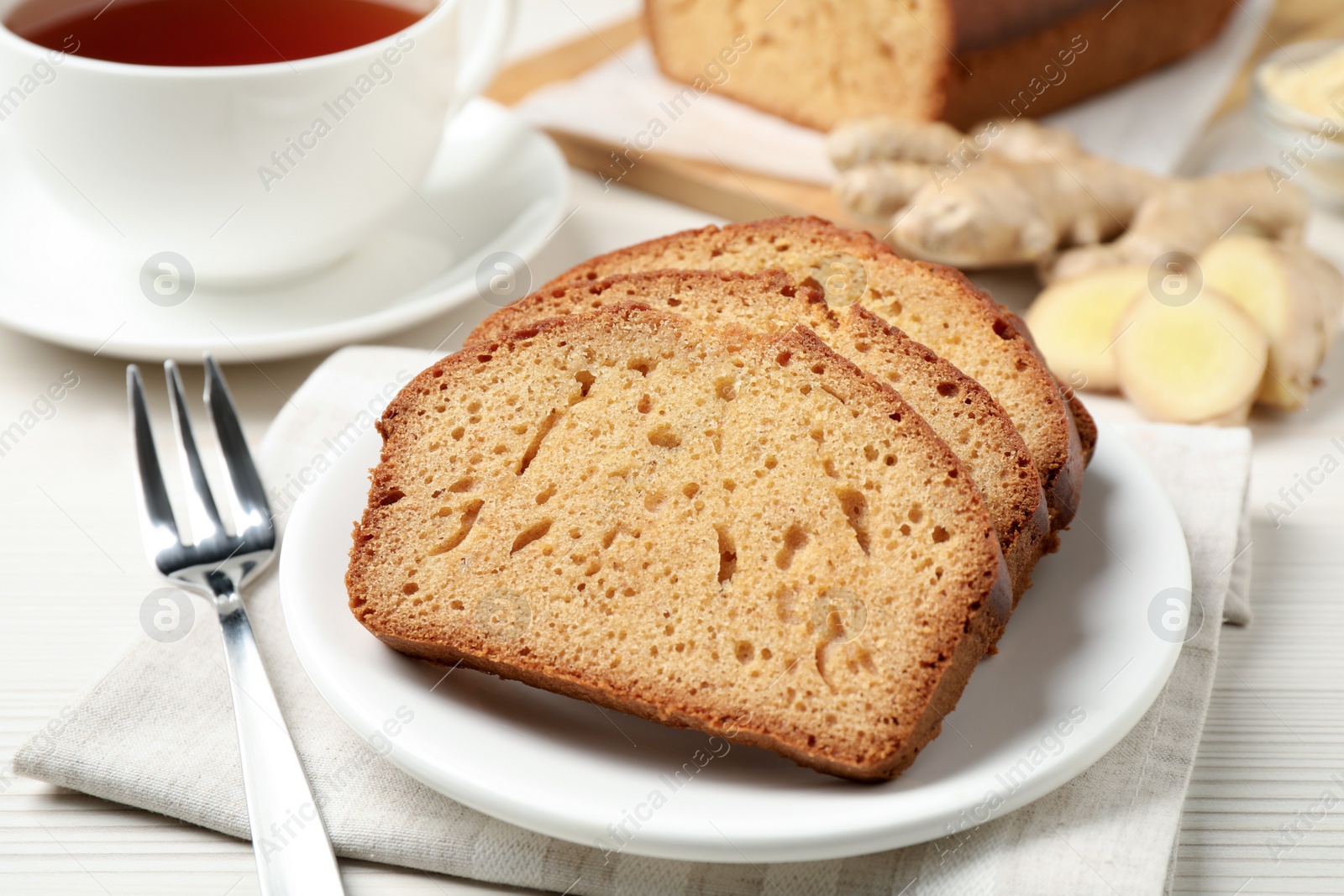 Photo of Slices of delicious gingerbread cake served with tea on white wooden table