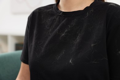 Woman with pet hair on her black clothers indoors, closeup