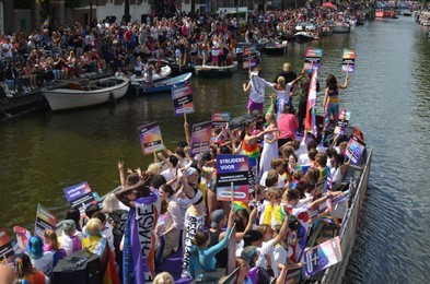 AMSTERDAM, NETHERLANDS - AUGUST 06, 2022: Many people in boats at LGBT pride parade on river