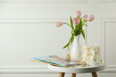 Different beautiful candles and tulips on white table, space for text. Stylish decor