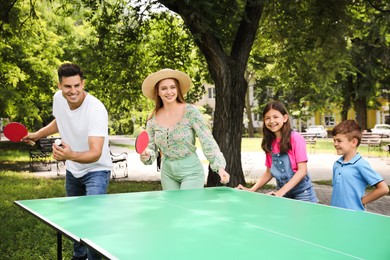 Photo of Happy family playing ping pong in park