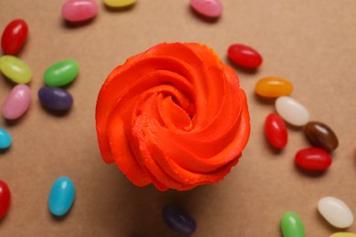 Delicious cupcakes with bright cream and candies on brown background, flat lay