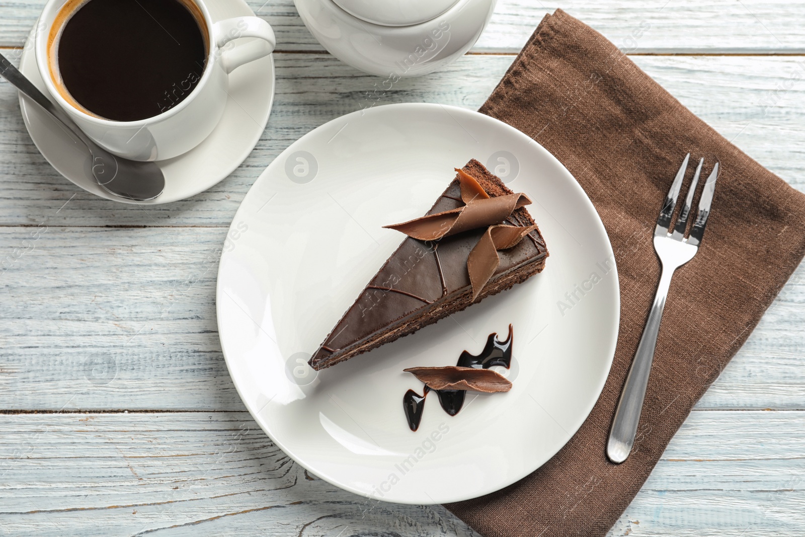 Photo of Slice of tasty chocolate cake and cup of coffee served on wooden table, top view