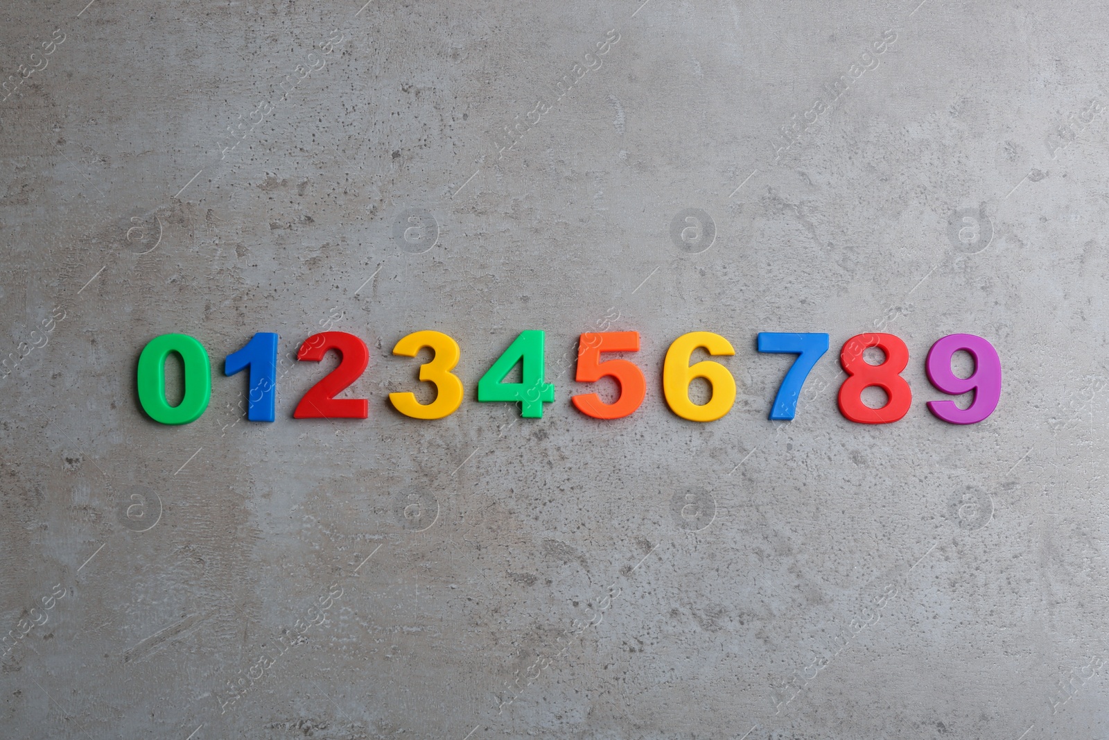 Photo of Colorful magnetic numbers on grey stone background, flat lay