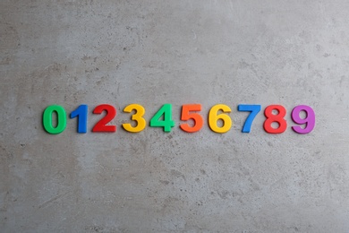 Colorful magnetic numbers on grey stone background, flat lay