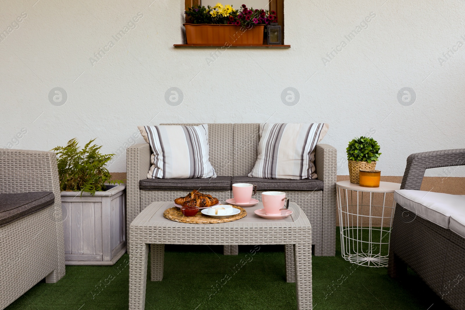 Outdoor breakfast with tea and croissants on rattan table on terrace Photo of Outdoor breakfast with tea and croissants on rattan table on terrace