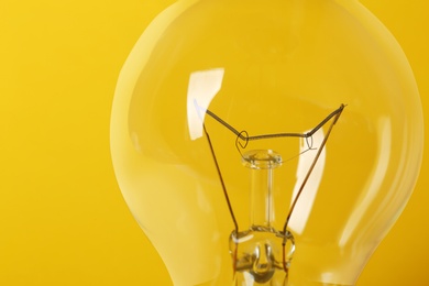 Photo of New modern lamp bulb on yellow background, closeup