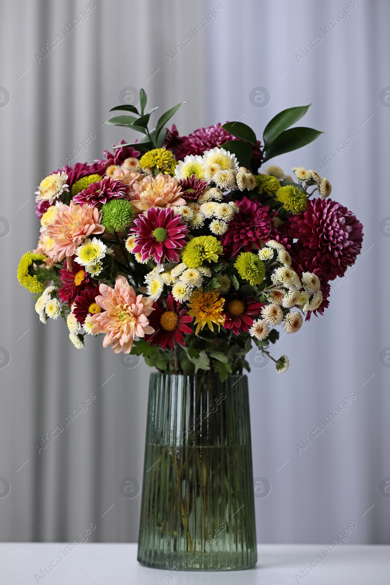 Photo of Bouquet of beautiful chrysanthemum flowers on table in room