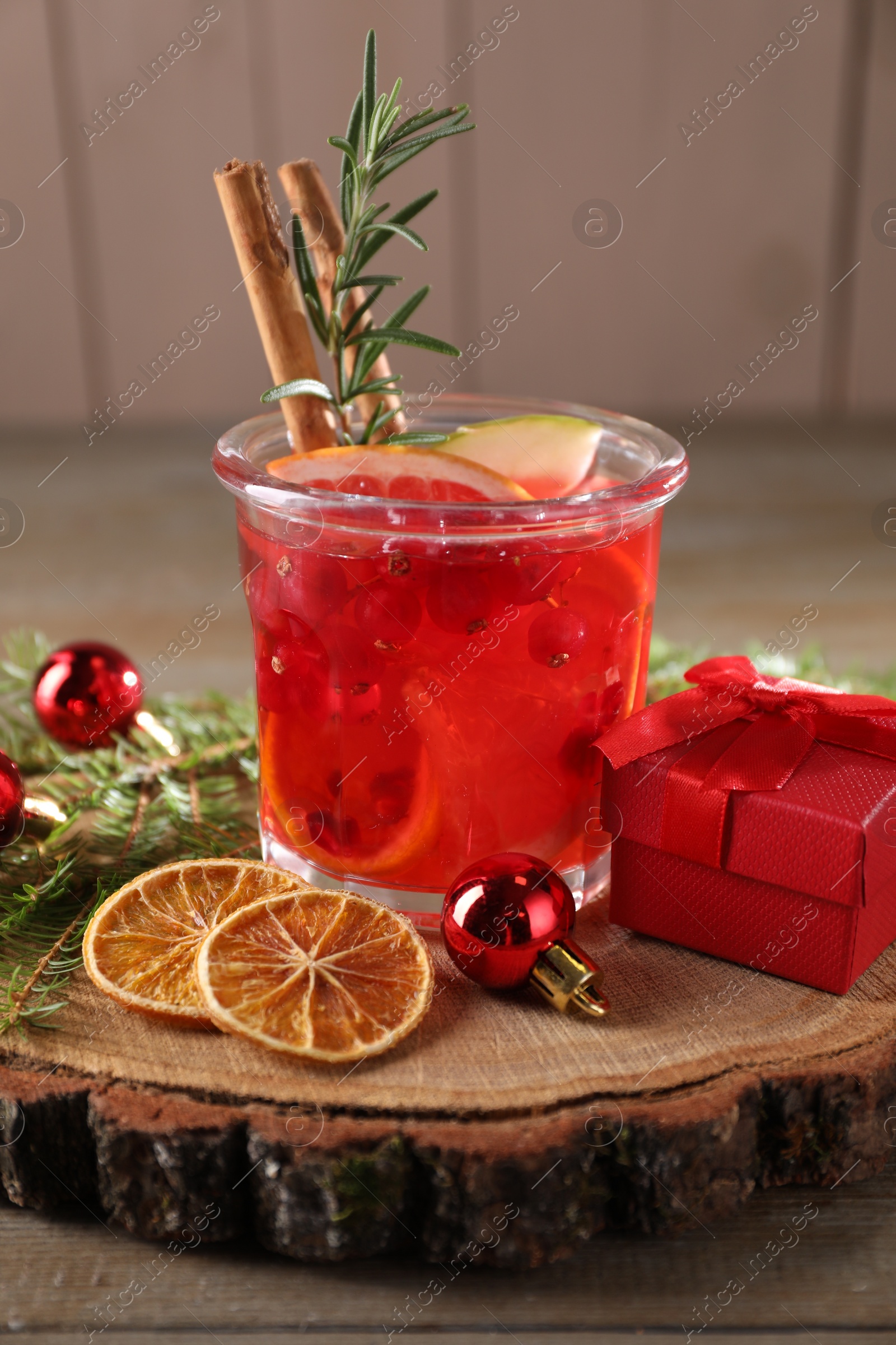 Photo of Aromatic Christmas Sangria in glass, gift box and festive decor on wooden table