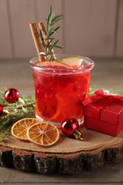 Photo of Aromatic Christmas Sangria in glass, gift box and festive decor on wooden table