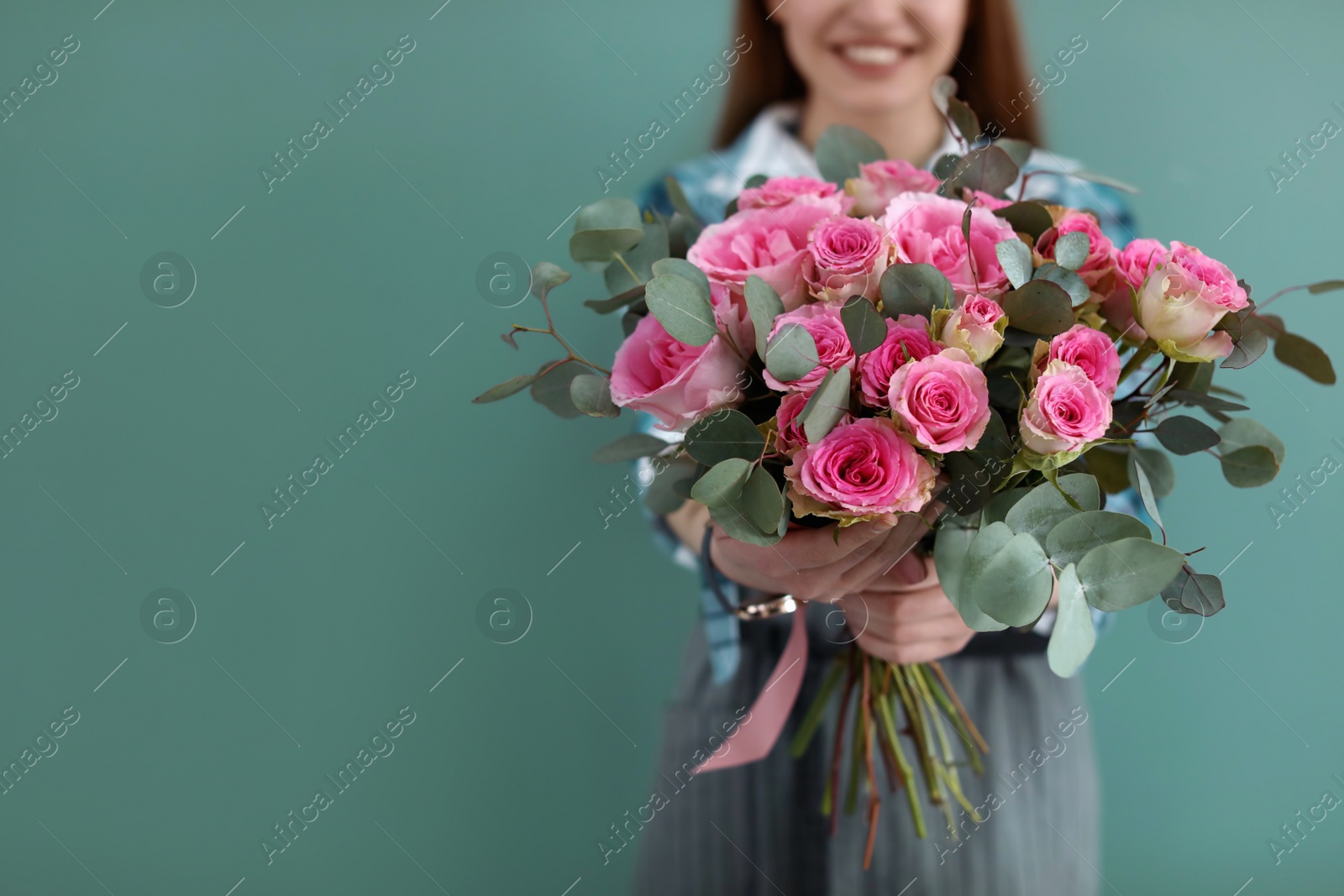 Photo of Female florist holding bouquet of beautiful flowers on color background