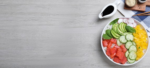 Photo of Delicious poke bowl with salmon and vegetables served on wooden table, flat lay. Space for text