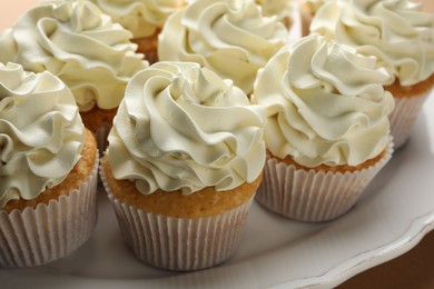 Tasty vanilla cupcakes with cream on table, closeup