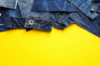 Photo of Flat lay composition with patches of old jeans on yellow background. Space for text