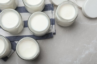Tasty yogurt in glass jars on light grey marble table, flat lay