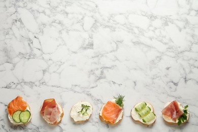 Photo of Delicious sandwiches with cream cheese and other ingredients on white marble table, flat lay. Space for text