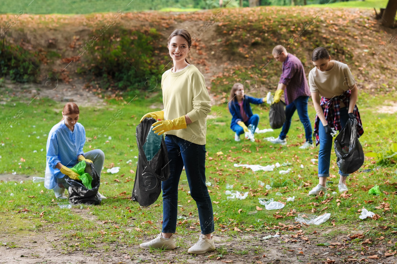 Photo of Group of people with plastic bags collecting garbage in park