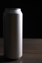 Photo of Aluminium can of energy drink on wooden table. Space for text