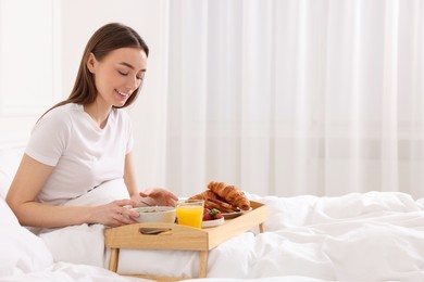 Photo of Smiling woman having breakfast in bed at home. Space for text