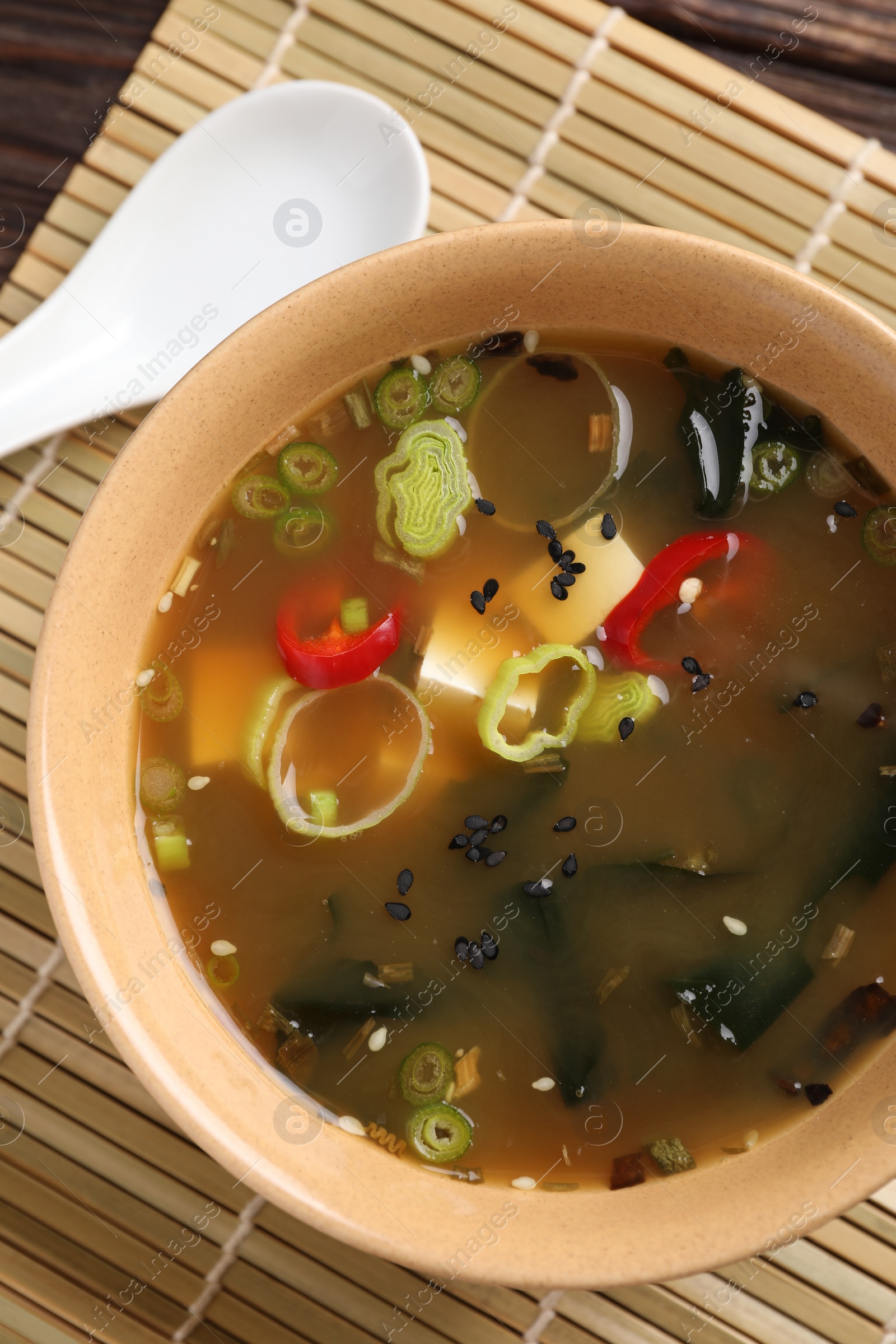 Photo of Bowl of delicious miso soup with tofu and spoon on table, top view