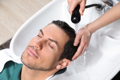 Photo of Stylist washing client's hair at sink in beauty salon