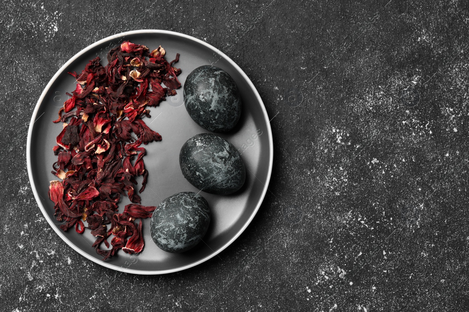 Photo of Naturally painted Easter eggs on black table, top view with space for text. Hibiscus used for coloring