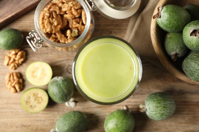 Photo of Fresh feijoa smoothie and fresh ingredients on wooden table, flat lay
