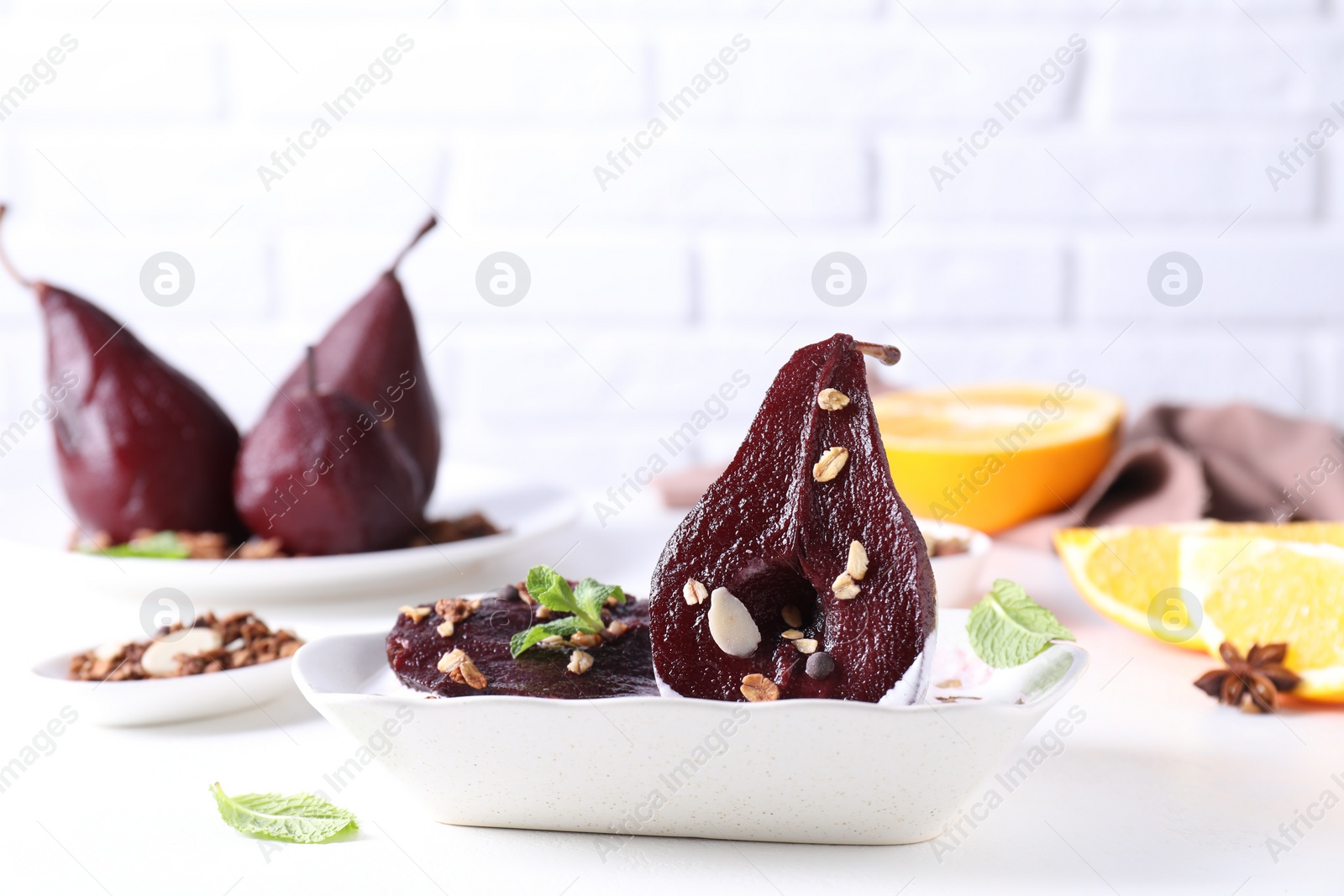 Photo of Tasty red wine poached pears with muesli and yoghurt in bowl on white table