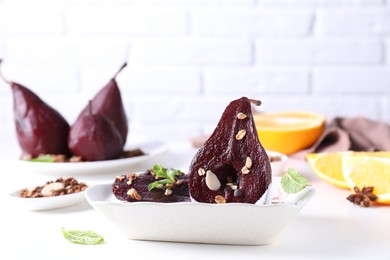 Tasty red wine poached pears with muesli and yoghurt in bowl on white table