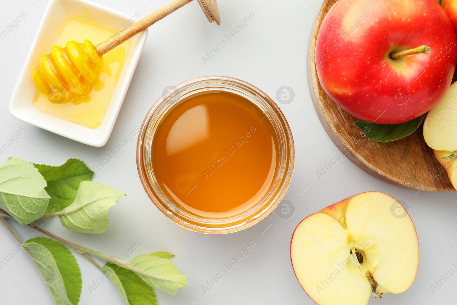 Photo of Sweet honey and fresh apples on white table, flat lay