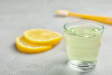 Glass with mouthwash and lemon on light background. Teeth care