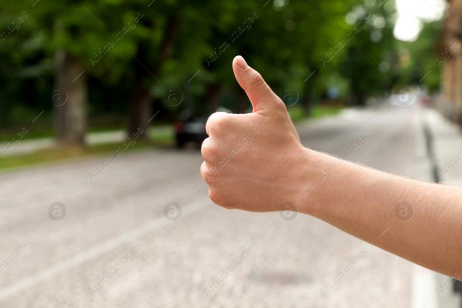 Photo of Man catching car on road, closeup and space for text. Hitchhiking trip