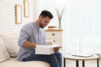 Photo of Man unpacking parcel at home. Online shopping