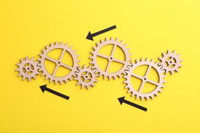 Photo of Business process organization and optimization. Scheme with wooden figures and arrows on yellow background, top view