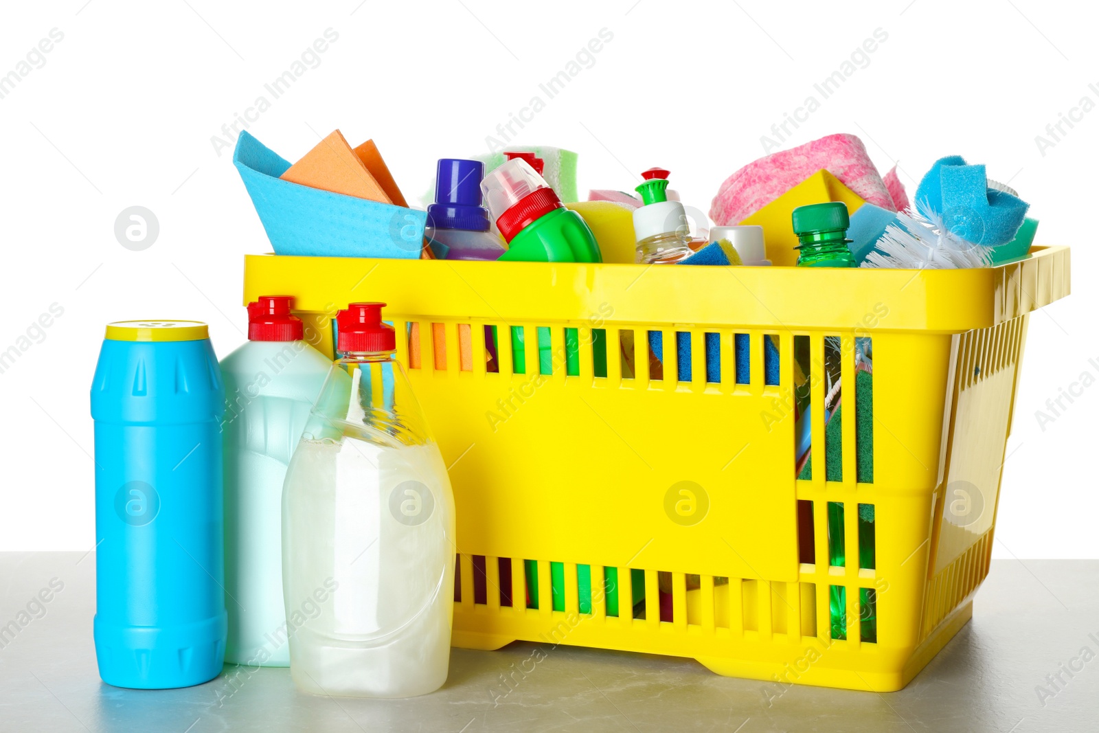 Photo of Shopping basket with different detergents on light grey marble table against white background